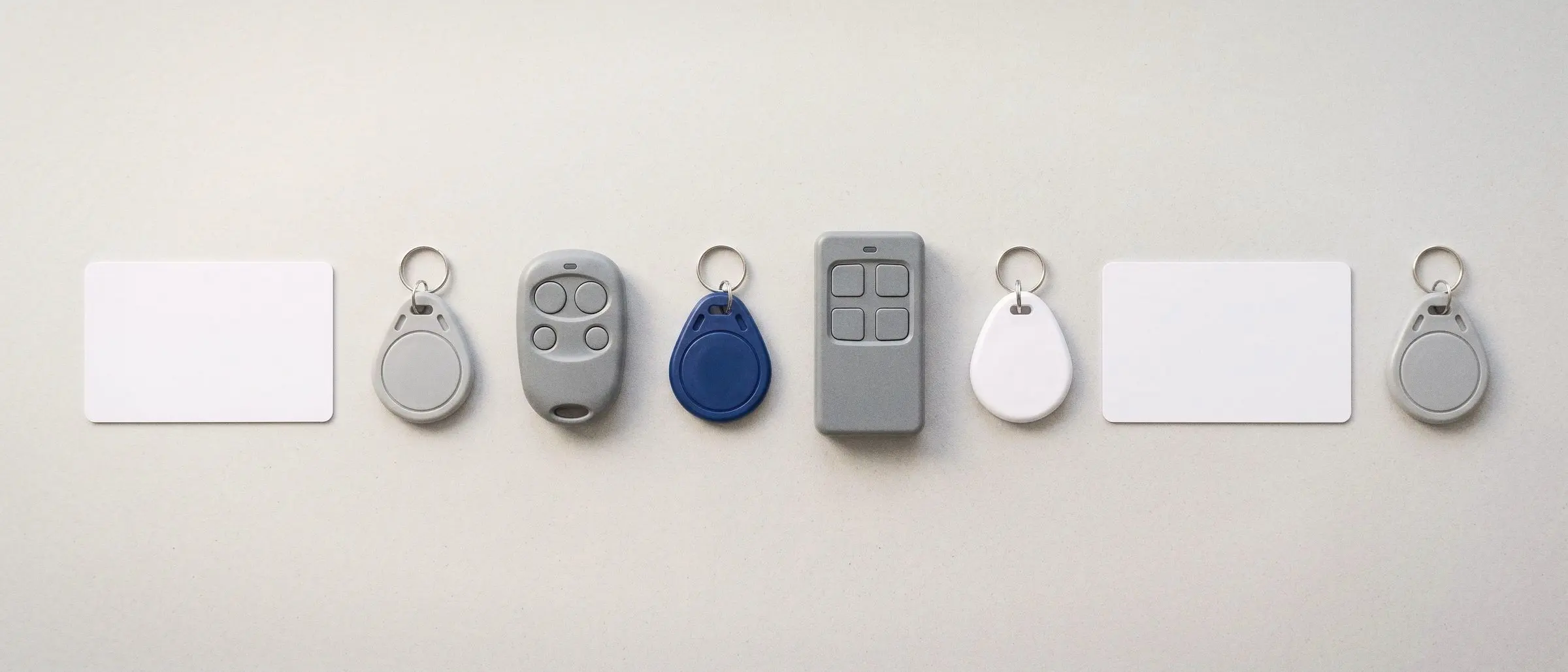 Badges d’immeuble et télécommandes alignés sur un fond clair